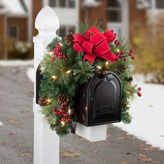 a mailbox decorated with christmas wreaths and lights on the front of a house