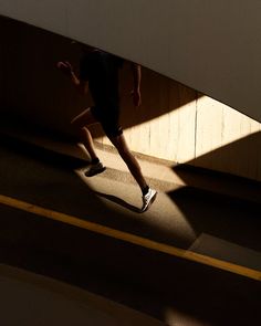 a person is running down the street under an overpass with their shadow on the ground