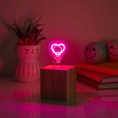 a pink light that is on top of a wooden block next to a potted plant