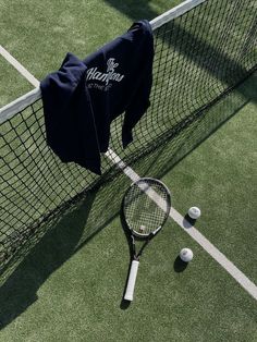 a tennis racket is laying on the ground next to a t - shirt and balls