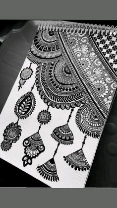 a black and white drawing on top of a notebook with an intricate design in the middle