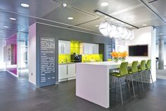 a kitchen with white counter tops and yellow chairs in it's center island area