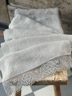 three pieces of linen with lace on them sitting on top of a wooden stool in front of a wall