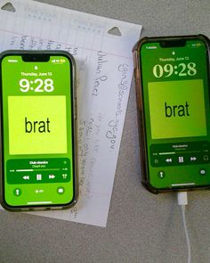 two green cell phones sitting next to each other on top of a table with paper