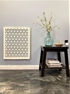 a vase filled with flowers sitting on top of a wooden table next to a wall