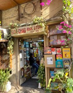 a store with lots of books and plants on the side of it's door