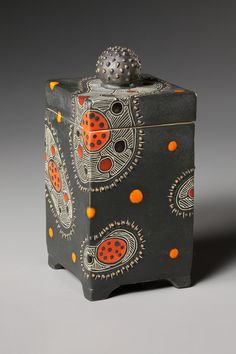 a black box with orange dots and a ladybug on the lid is shown