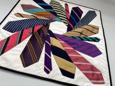 a multicolored tie quilt is displayed on a white tablecloth with black border