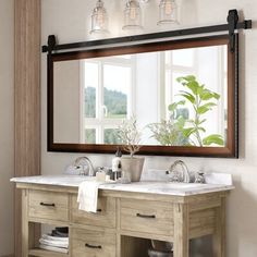 a bathroom vanity with two sinks under a large mirror and hanging lights above the sink