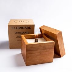 a wooden box with a lit candle in it and the lid open to show its contents