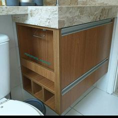 a bathroom with a toilet, sink and wooden cabinet above the toilet is a roll of toilet paper