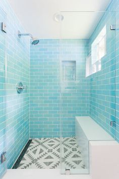 a bathroom with blue tiles on the walls and floor, along with a walk in shower