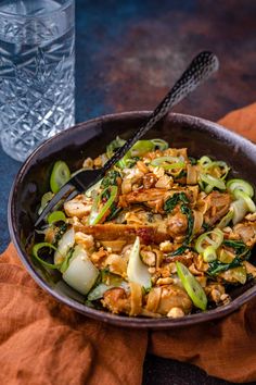 a bowl filled with food next to a glass of water