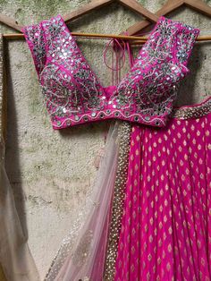 A three-piece fuchsia mirror zari lehenga set from the Priti Sahni collection. This gorgeous georgette fuchsia butti lehenga with a heavy zari border of sequin work is paired with a raw silk fuchsia mirror blouse in pearl, and zardozi hand embroidery. The lehenga has side hanging ball tassels to the waistline. And the blouse has pearl tassel tie-up at the back. This outfit is completed with a hand-embroidered butti nude tulle dupatta in net material with gota-sequin-pearl work border detail. Pink Sequined Pre-draped Saree For Festivals, Pink Cutdana Lehenga For Party, Pink Pre-draped Saree With Gota Work For Navratri, Pink Chandbali Set With Mirror Work, Pink Sequined Lehenga For Diwali, Bollywood Style Pink Sequined Choli, Pink Floor-length Saree With Gota Work, Pink Floor-length Cutdana Blouse Piece, Pink Pre-draped Saree With Gota Work For Reception