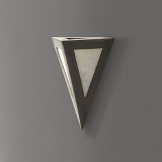 a wall mounted vase with a triangular design on the front and back of it, against a gray background