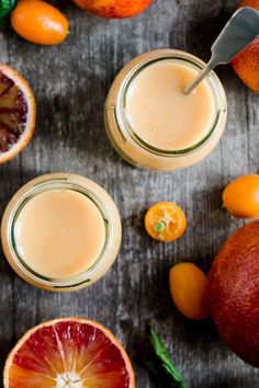 two glasses filled with orange juice surrounded by citrus fruits