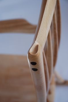 the back end of a wooden chair with black dots on it's seat cushion