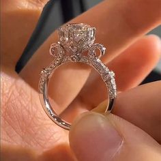 a close up of a person's hand holding an engagement ring