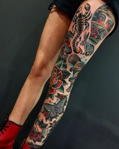 a woman's leg with tattoos and red shoes on it, showing her legs