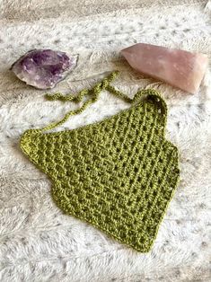 a green crocheted purse sitting on top of a white blanket next to some rocks