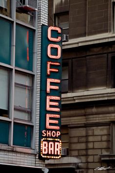 a neon sign on the side of a building that says coffee shop bar in front of it