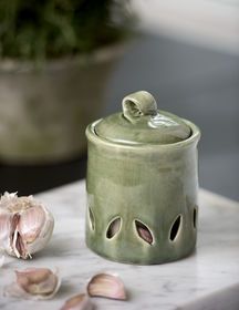 a garlic plant sitting on top of a table next to a ceramic container with holes in it