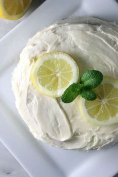 a white plate topped with a cake covered in frosting and lemon slices