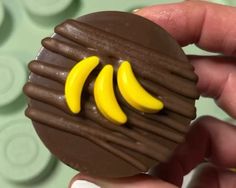 a hand holding a chocolate candy with banana slices on it's side and the top half is made out of legos