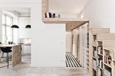 an open living room and dining area with bookshelves in the center, stairs leading up to the second floor