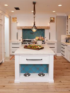 a kitchen with blue and white tiles on the wall, an island in the middle