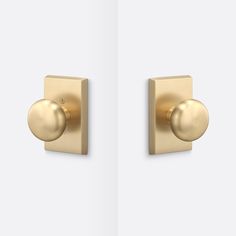 two gold door knobs on the side of a white wall, one with a round handle