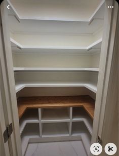 an empty walk in closet with white shelves and wood flooring on the bottom shelf