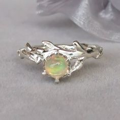 This is a opal ring, which has a genuine cabochon opal prong setting surrounded by silver vine leaves in the center of the ring, and the band is decorated with silver vine leaves and twigs. REMARK : The natural gemstones would have natural inclusions and slightly vary from the photos. MATERIAL - Cabochon opal - 925 sterling silver MEASUREMENT - Ring size : 7 US - Cabochon opal size : 6 mm x 6 mm HOW TO ORDER 1. Measure your finger size to ensure that the ring would fit your finger properly. 2. L Silver Moonstone Ring With Ethiopian Opal, Silver Ethiopian Opal Ring With Cabochon, Nature-inspired Opal Ring Gift, Silver Ethiopian Opal Ring, Silver Cabochon Opal Promise Ring, Silver Ethiopian Opal Ring For Promise, Silver Ethiopian Opal Promise Ring, Unique Sterling Silver Opal Wedding Ring, Unique Sterling Silver Opal Ring For Wedding