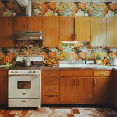 a kitchen with wooden cabinets and floral wallpaper on the walls, along with an oven