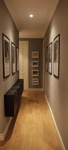 a long hallway with pictures on the wall and wooden flooring in front of it