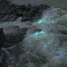 the waves are crashing against the rocks by the ocean's edge at night time