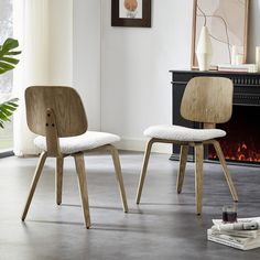 two wooden chairs sitting next to each other in front of a fireplace