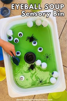 a child's hand is using scissors to make an eyeball soup activity bin