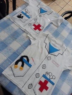 three children's shirts with penguins on them are sitting on a blue and white checkered tablecloth