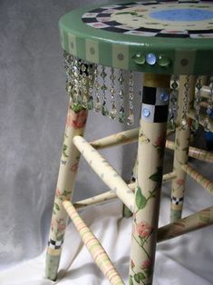 a stool made out of wooden sticks with beaded trimmings on the legs