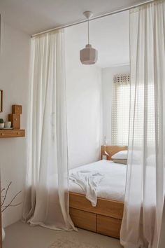 a bedroom with white walls and curtains on the windowsills, along with a bed