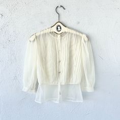 "S p e c i f i c s . . . Label: Paulwin Tagged Size: -- Approx Fit: XS - S Color: White Material: Nylone Sheer Material // Buttons  Condition: Overall in Amazing Vintage Condition M e a s u r e m e n t s . . . (side to side // laying flat // closed) Bust - approx. up to 21\" Waist - approx. 14\" Length - approx. 22\"" Summer Button-up Top With Sheer Sleeves, Classic Sheer Button-up Tops, Vintage Long Sleeve Sheer Tops, Sheer Fitted Button-up Blouse, Fitted Sheer Button-up Blouse, Chic Vintage Spring Tops, Chic Fitted Tops For Vintage Fashion, Vintage Sheer Blouse For Spring, Vintage Sheer Blouse For Parties