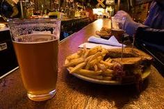 a plate of french fries next to a glass of beer on a table in a bar