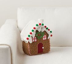 a small gingerbread house sitting on top of a white couch next to a pillow