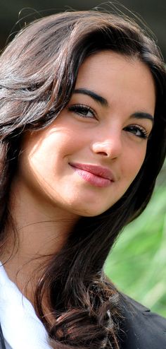 a close up of a person wearing a suit and tie with long hair smiling at the camera