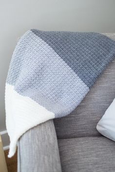 a gray and white blanket sitting on top of a couch