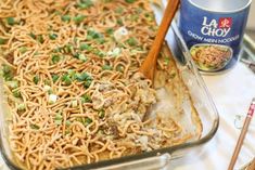 a casserole dish with noodles, meat and vegetables in it next to chopsticks