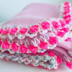 two pink and white crocheted blankets folded on top of each other