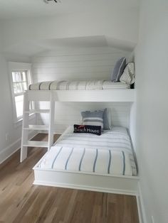 a bunk bed sitting in the corner of a room next to a wooden floor and white walls