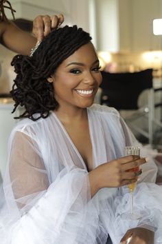 a woman in a white dress is holding a wine glass and smiling at the camera